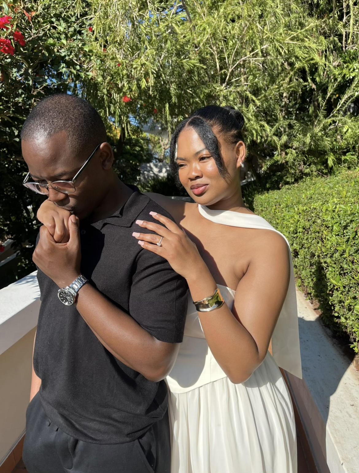 Chukwuma kissing Ellen's hand as she rests it on his shoulder, showing her engagement ring